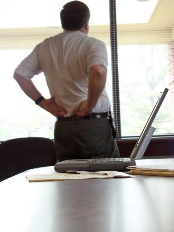 Homme dans un bureau avec douleur au bas du dos